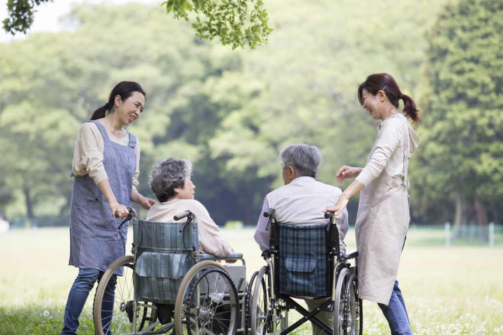 公園で車椅子の入居者と職員が一緒に過ごす風景。屋外レクリエーション活動。