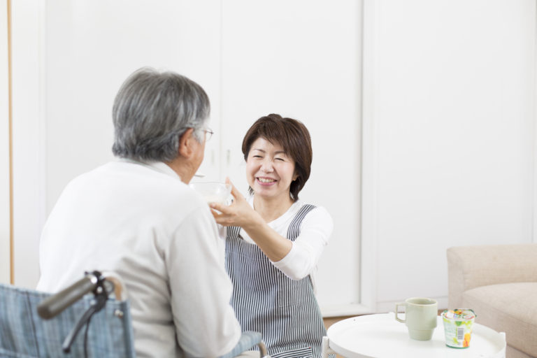 介護職員が高齢入居者と談笑する共用スペースの風景